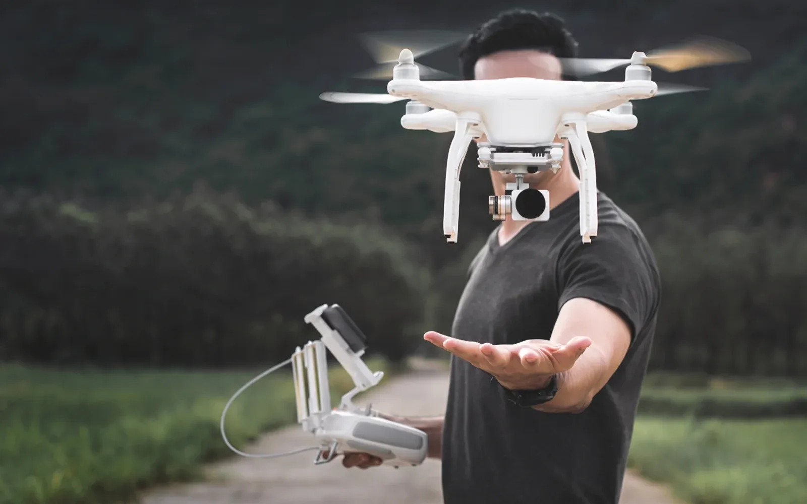 Mann som lander en hvit drone i hånden